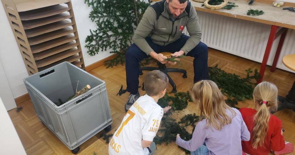 Waldaufseher und Kinder beim Adventkranzbinden